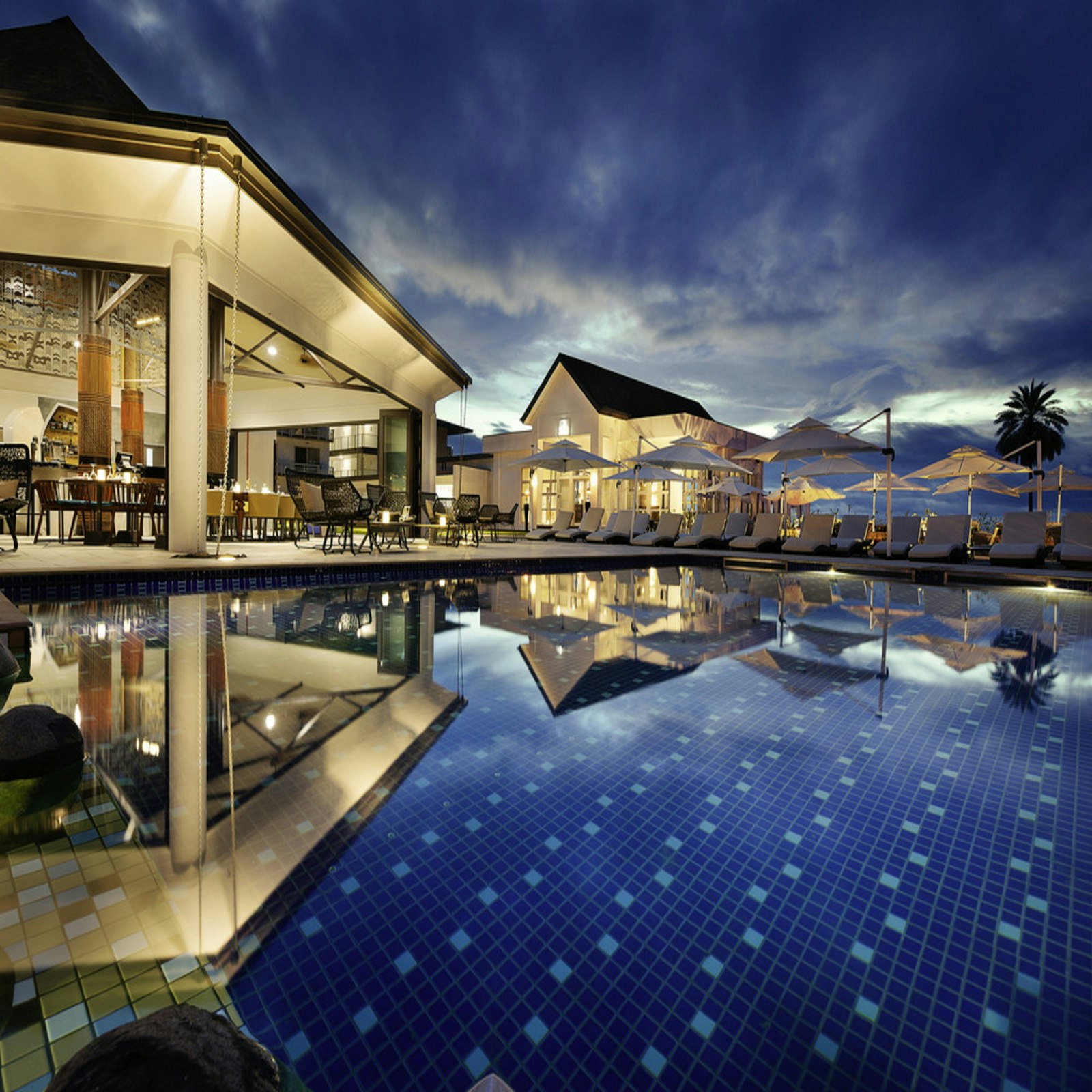 Luxury resort pool at sunset with palm trees